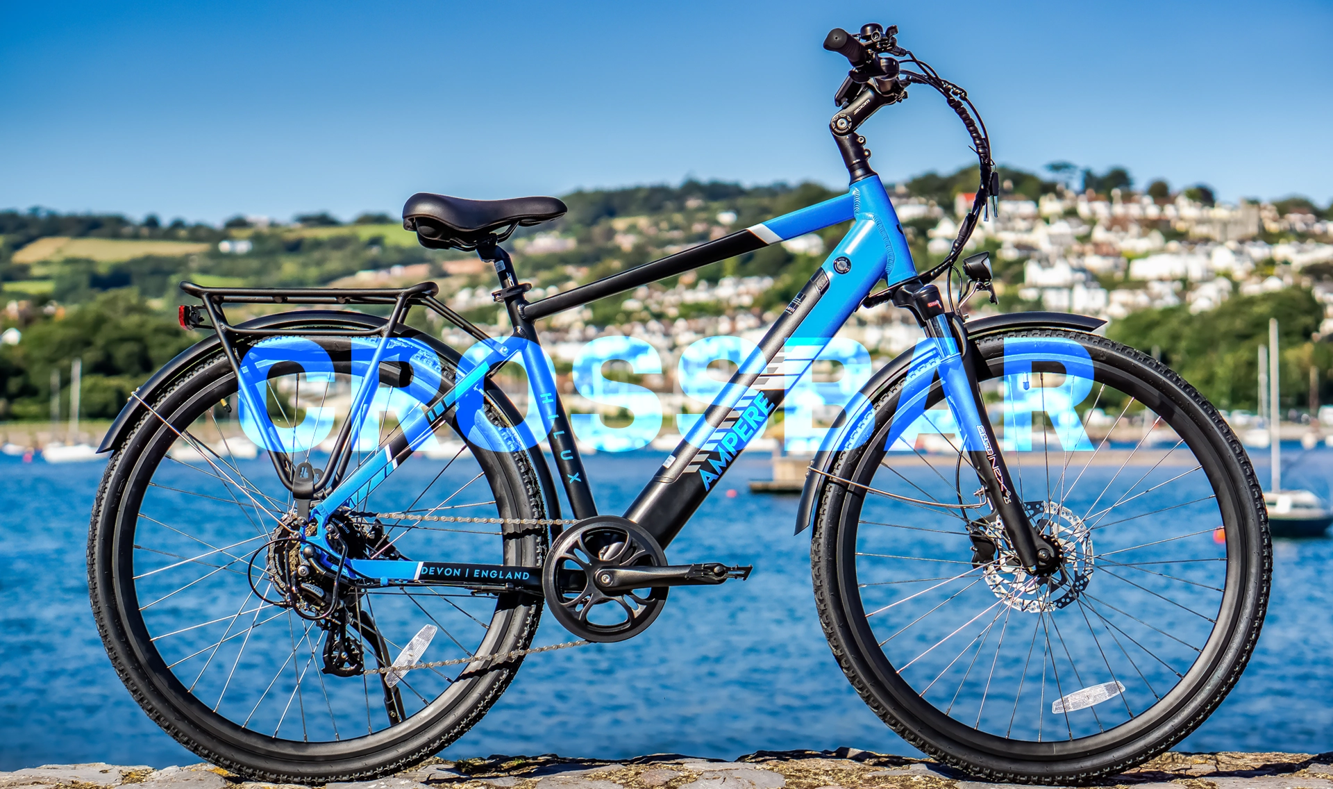 A blue Ampere Electric crossbar bike in front of a harbour.