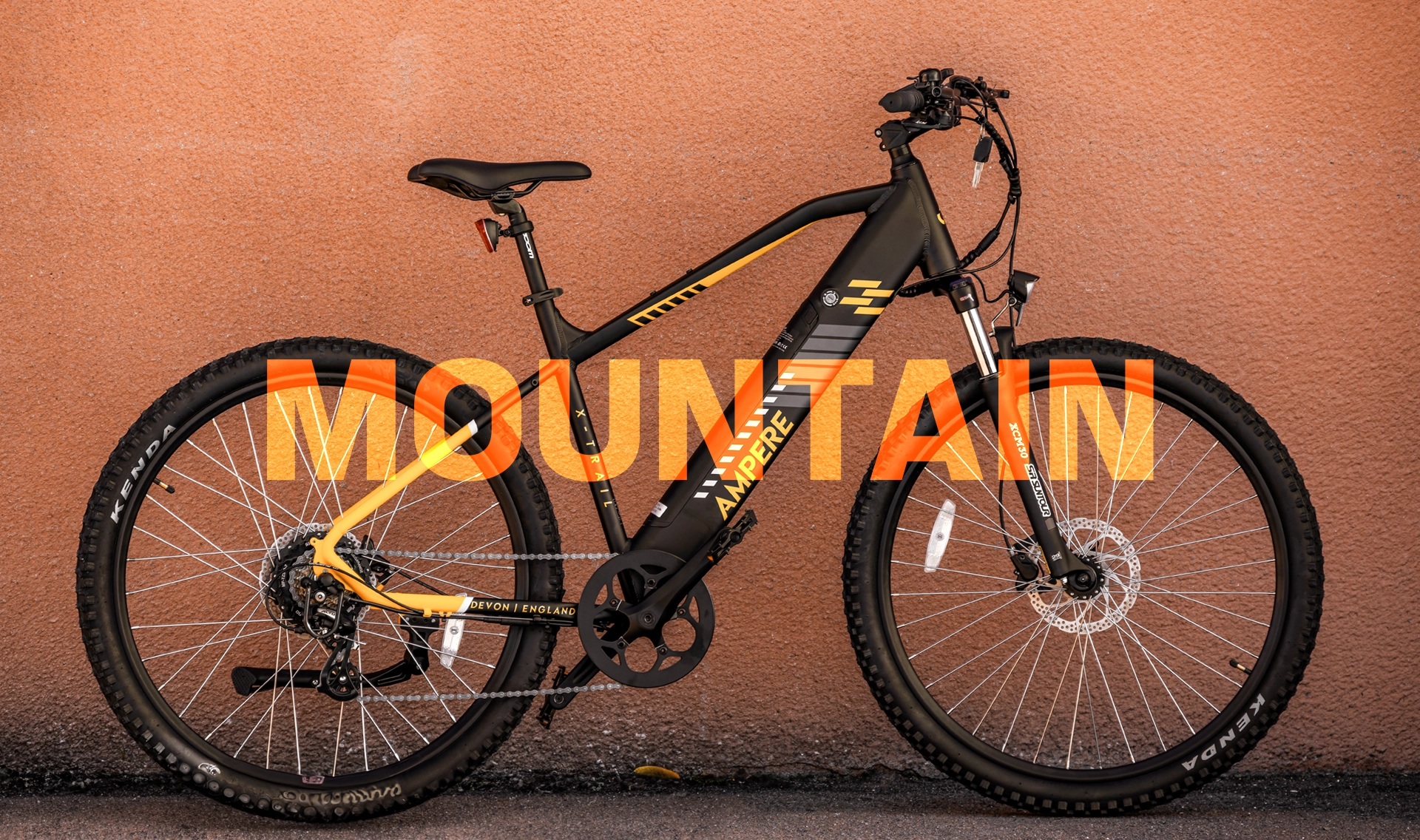 A black and yellow Ampere Electric mountain bike in front of an orange wall